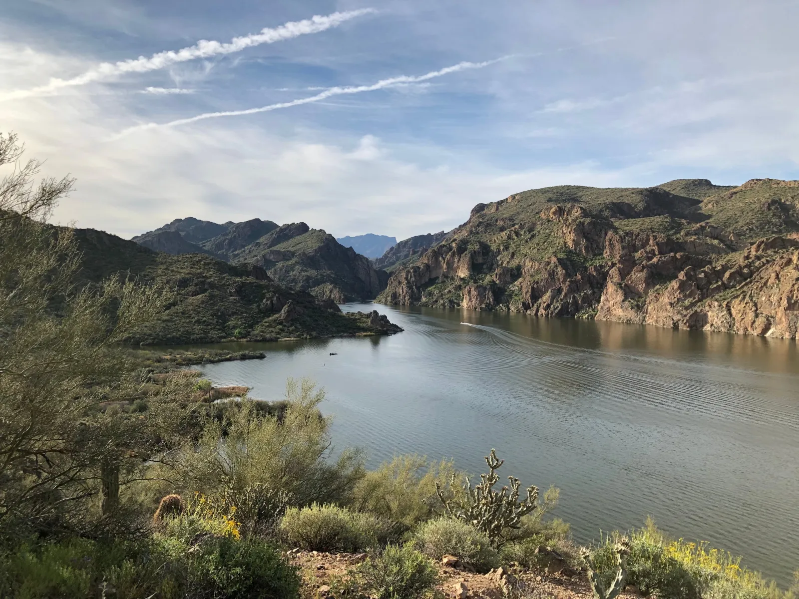 A winding lake between rocky Arizona canyon walls beneath streaked clouds.