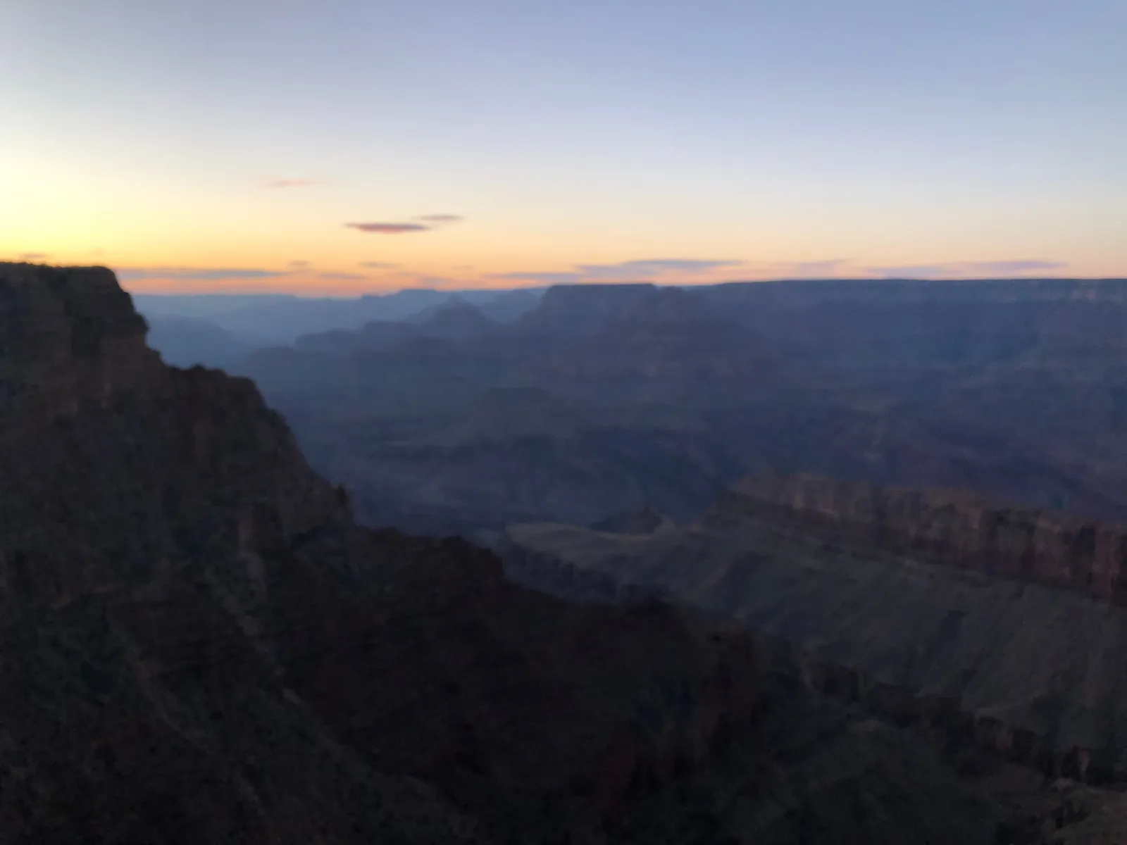 Layered canyon walls fading into the distance beneath an orange and blue evening sky.