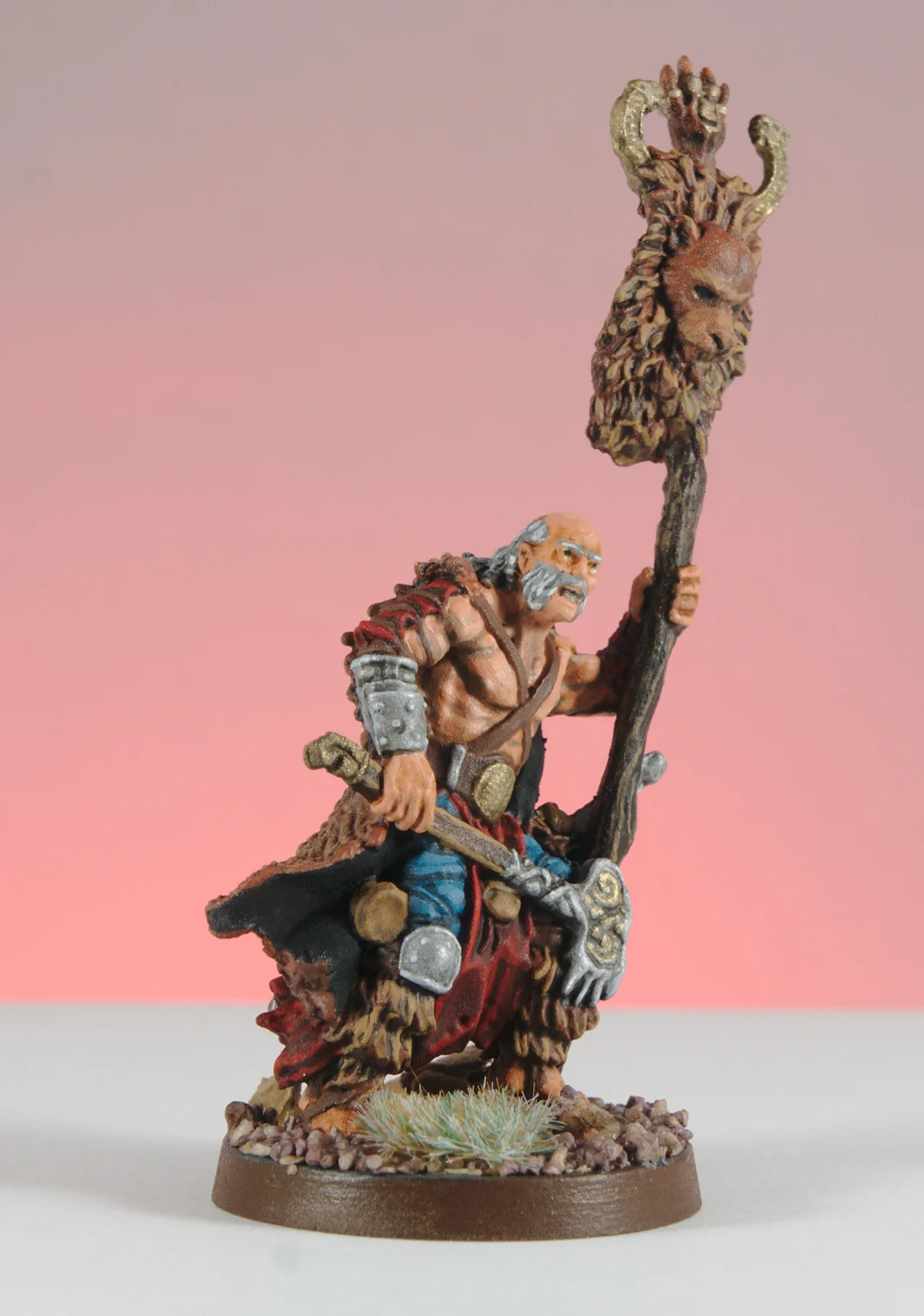Front view of the painted Bear Clan leader holding a tall bear-topped standard, with turquoise fabric and snow on the base.