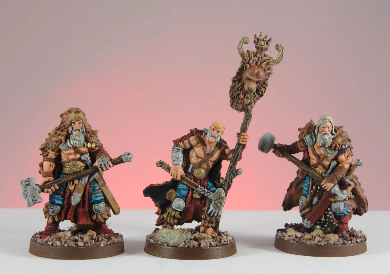 Three painted Blood Rage Bear Clan figures with turquoise accents and snowy bases against a pink background.